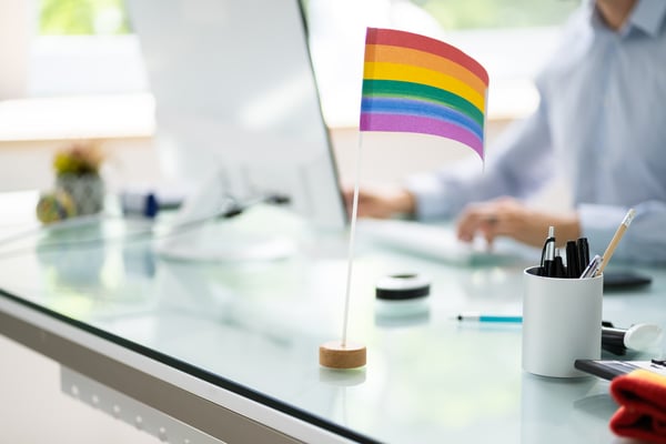  gay pride flag on a desk of a man working on a computer