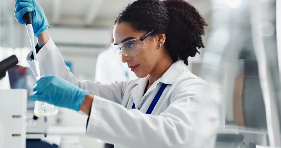 woman scientist in laboratory wearing googles performing a chemistry experiment